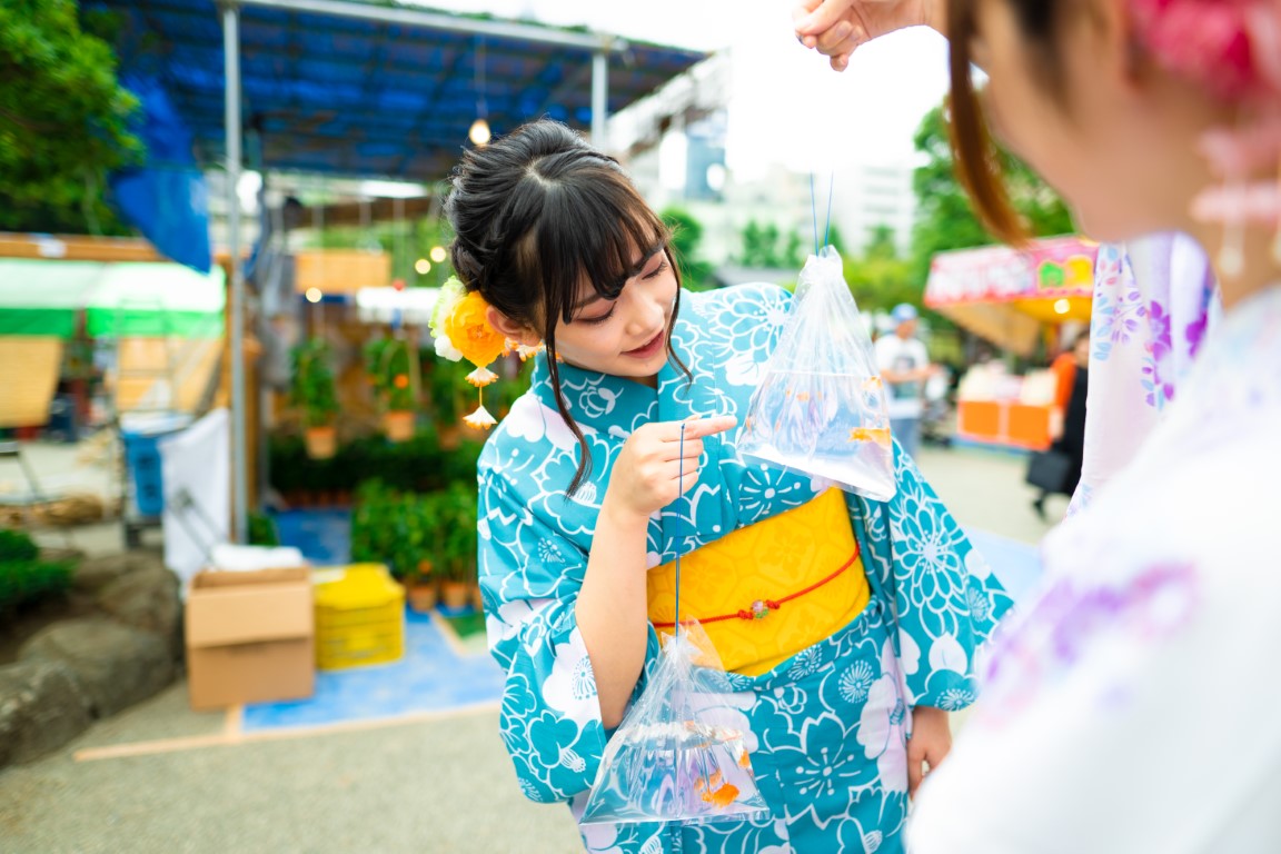 浴衣姿で金魚の袋を持っている女性