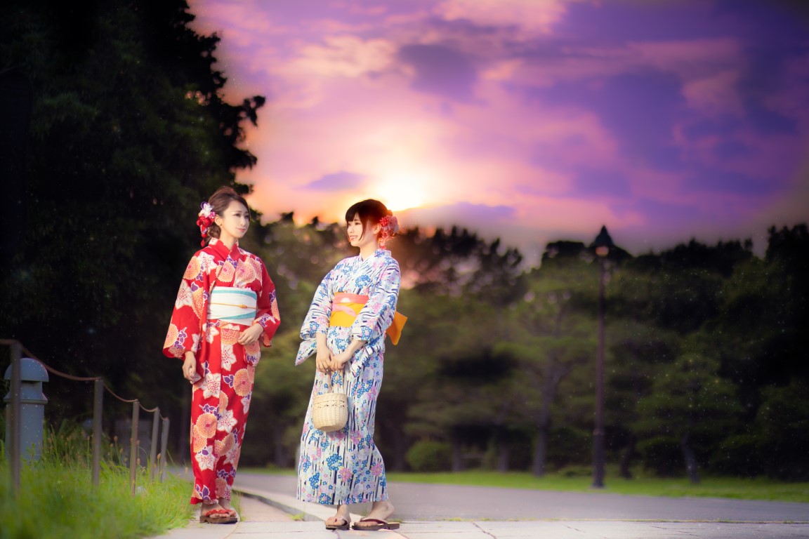 2人組の女性が浴衣着て夕暮れの公園を歩いている