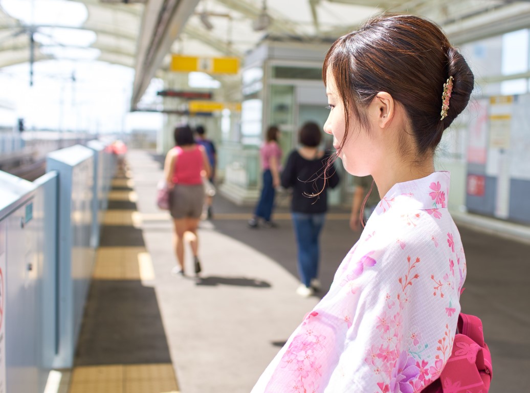 着物姿の女性が駅のホームで電車を待っている